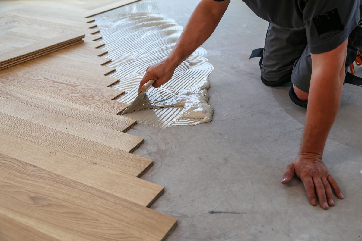 A skilled worker laying down wood flooring, showcasing expertise in flooring service within a home environment.