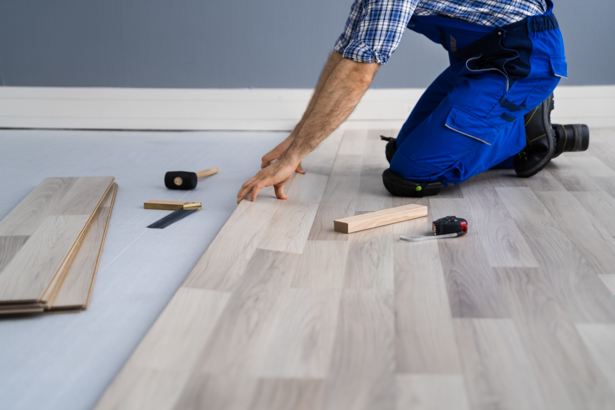 A man installing wood flooring, demonstrating the importance of selecting the right flooring contractor for quality work.