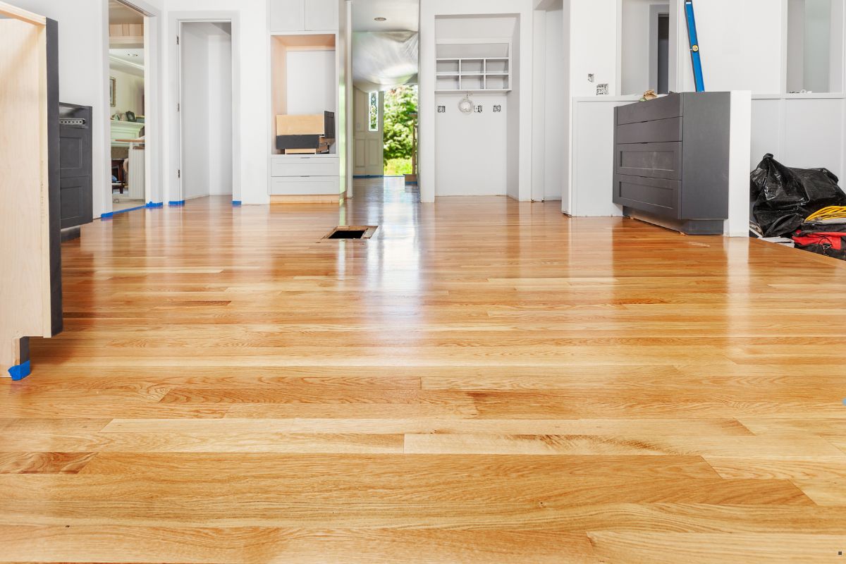 A polished hardwood floor in a bright kitchen, emphasizing the skill of professional flooring services.