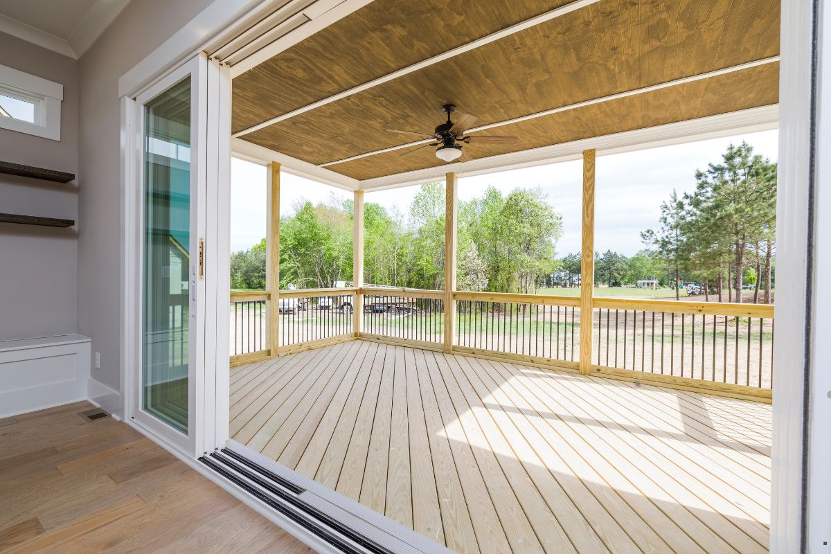 A screened porch featuring a sliding door and wooden flooring, showcasing quality craftsmanship from a flooring service.