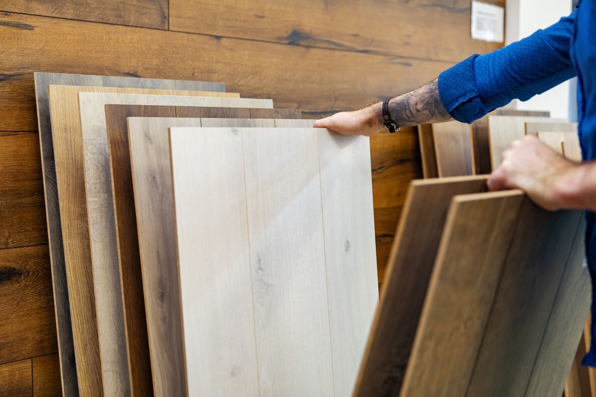 A man displays a stack of wood panels, representing diverse options for flooring selections in interior design.